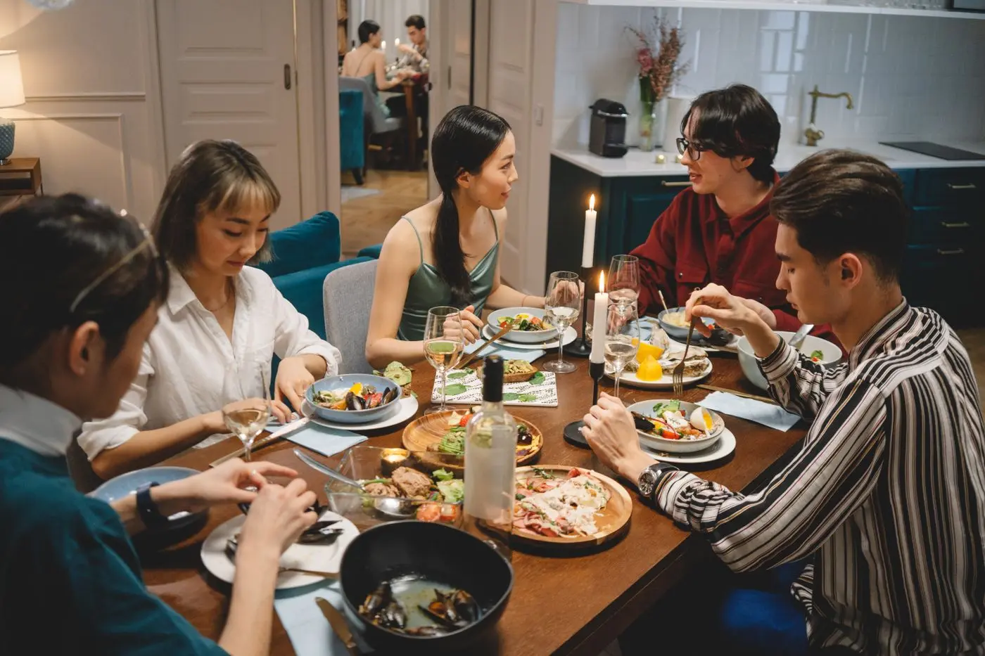 Friends talking and sharing dishes around a home dining table