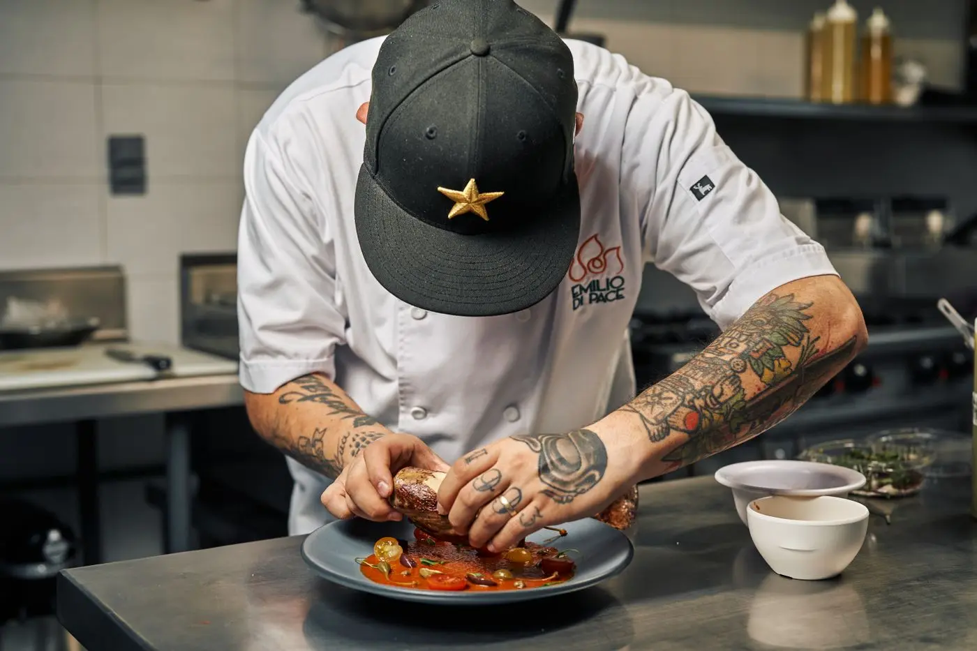 A chef carefully finishing a dish in a working kitchen