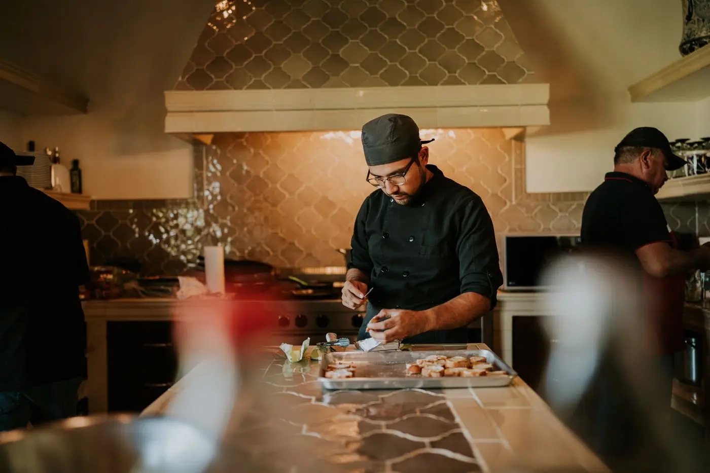 A host concentrating on finishing dishes in a warm working kitchen