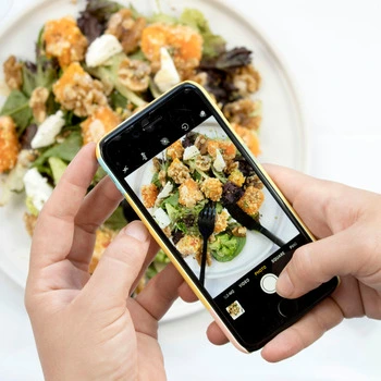 A person taking a picture of a plate of food.