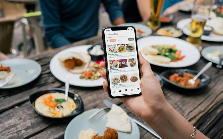 A person holding a phone showing a food-based platform.